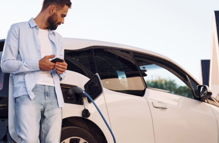 Man standing by electric car while charging