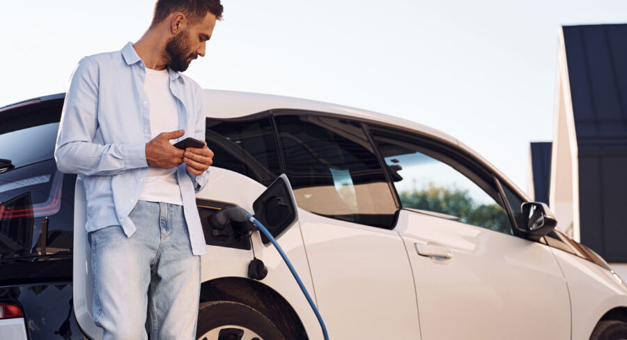 Man standing by electric car while charging