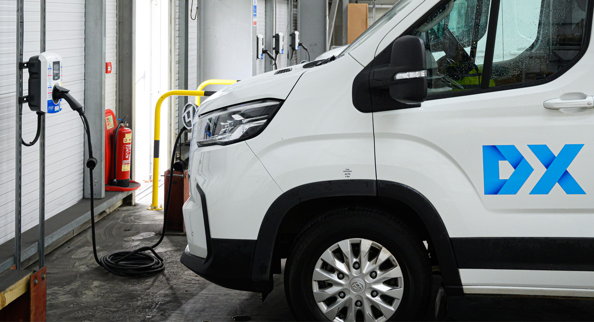 DX white delivery van plugged into charge point