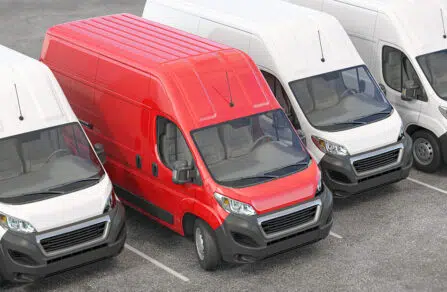 Row of parked white vans with red van standing out in centre