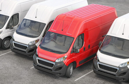 Row of parked white vans with red van standing out in centre