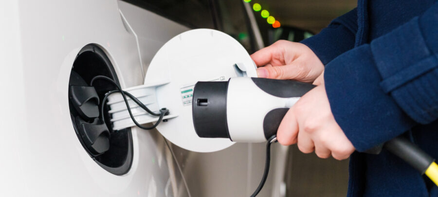 White electric car with charging cable entering charging port